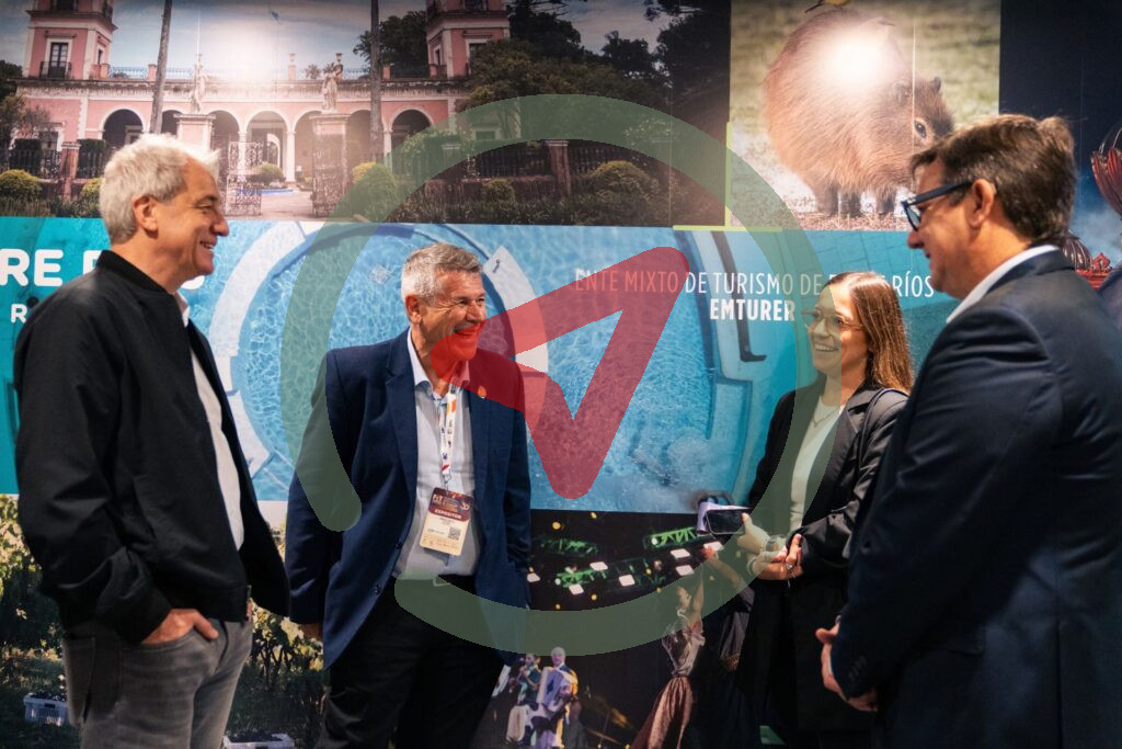 Cuatro participantes conversan frente a un panel del stand de Turismo de Entre Ríos.