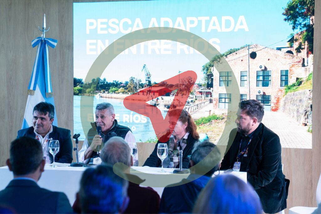 Mesa de presentación de pesca adaptada en la FIT, frente a una pantalla que dice Pesca adaptada en Entre Ríos.